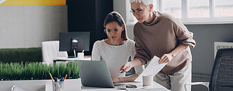 Zwei selbstbewusste Geschäftsfrauen schauen auf den Computerbildschirm, während sie zusammen im Büro arbeiten