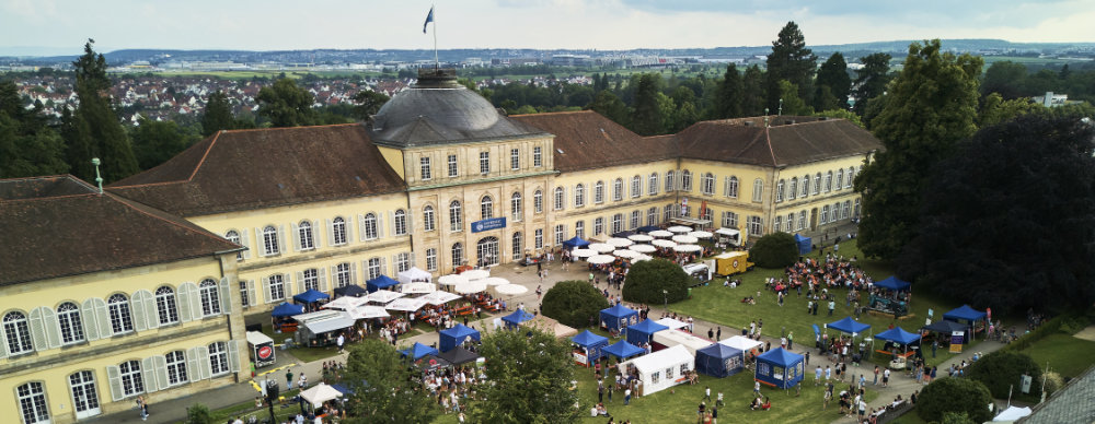 Luftbild des Schlosses Hohenheim Innenhof mit vielen aufgebauten Zelten und Menschen.